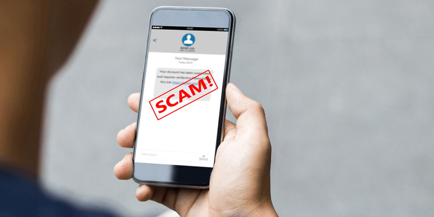 A man holding a phone with a scam text alert.