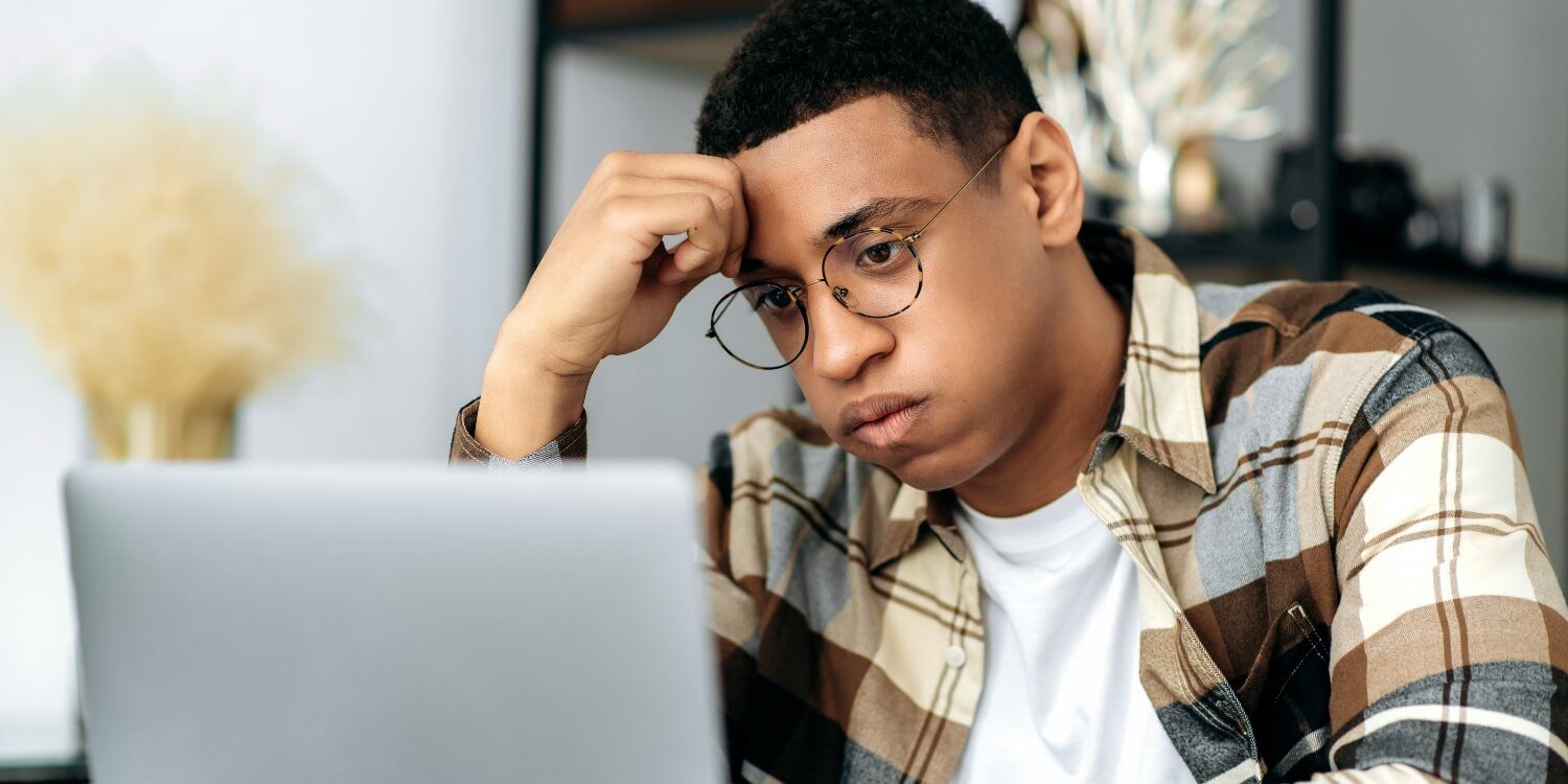 A man looking stressed whilst looking at his laptop