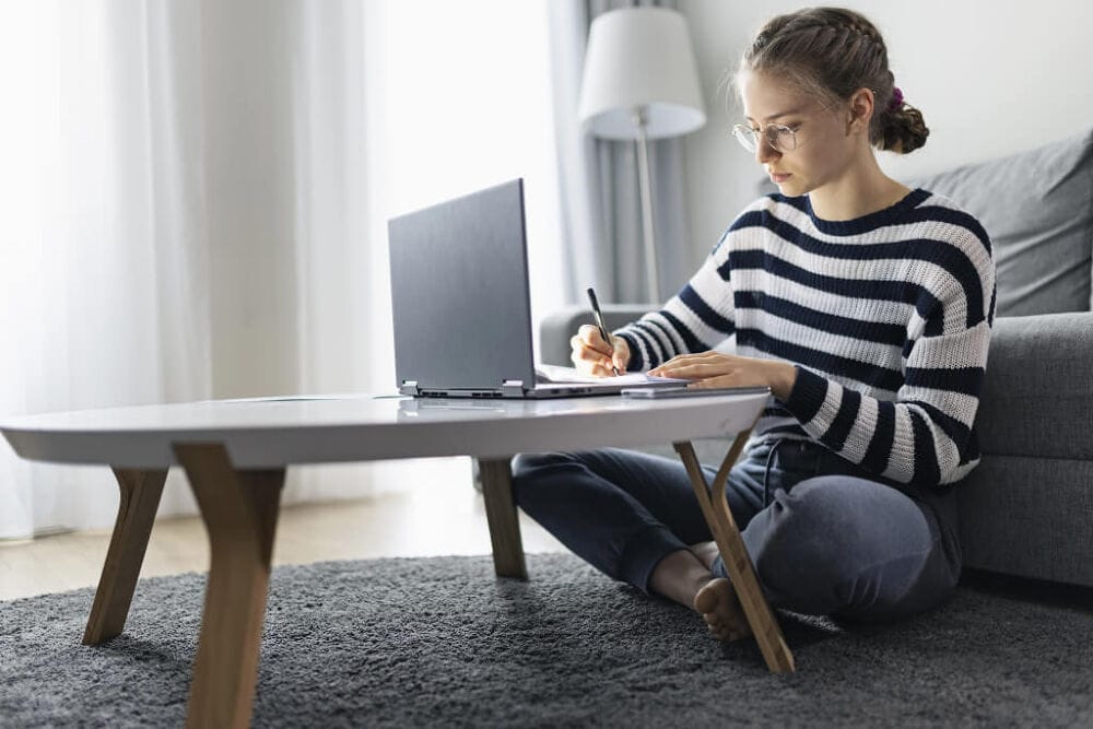 A woman working on her laptop in the living room