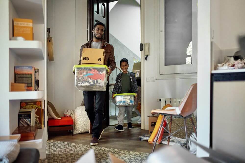 A man and a boy moving boxes into a room