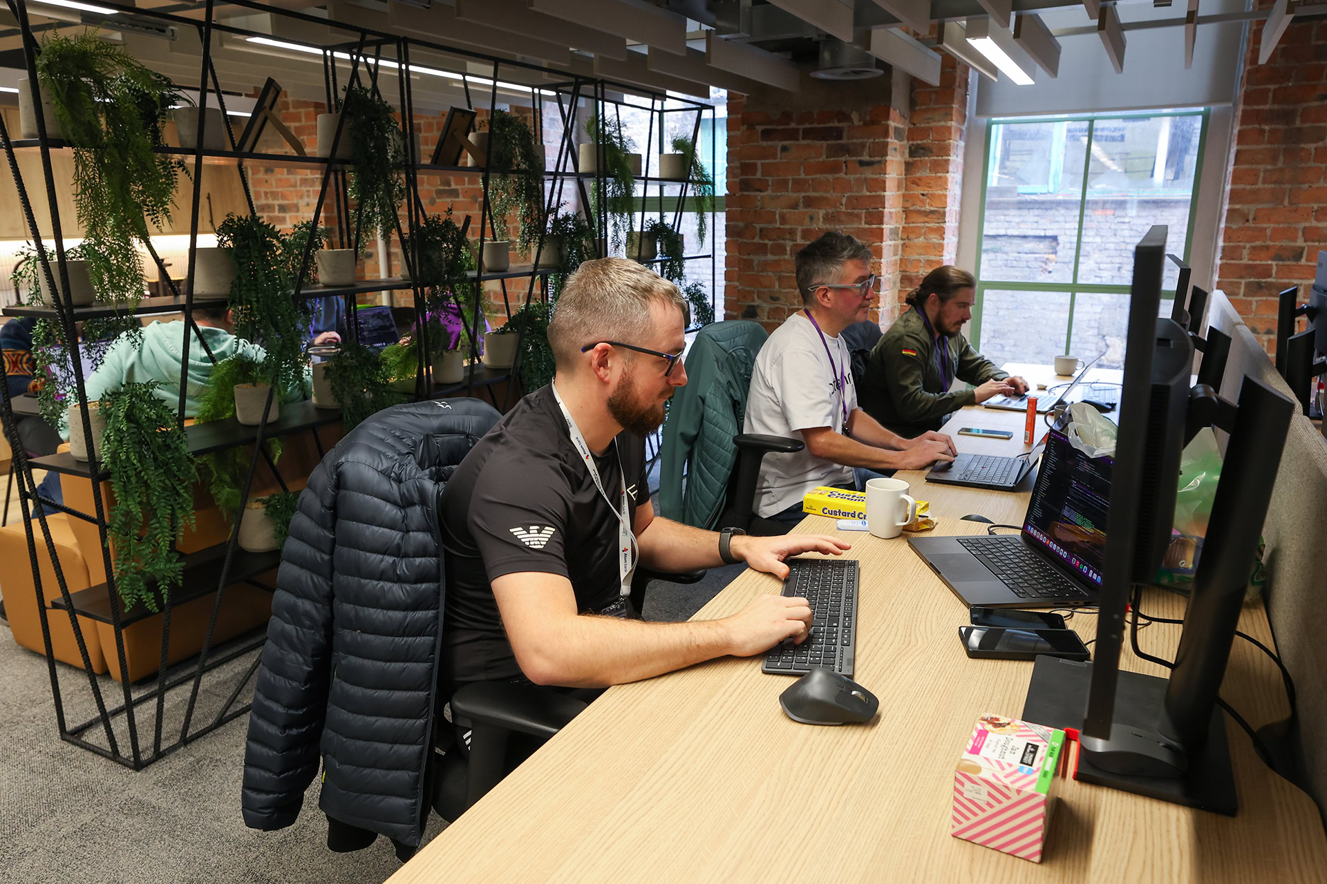 Three people sitting at their desks and working on their computers