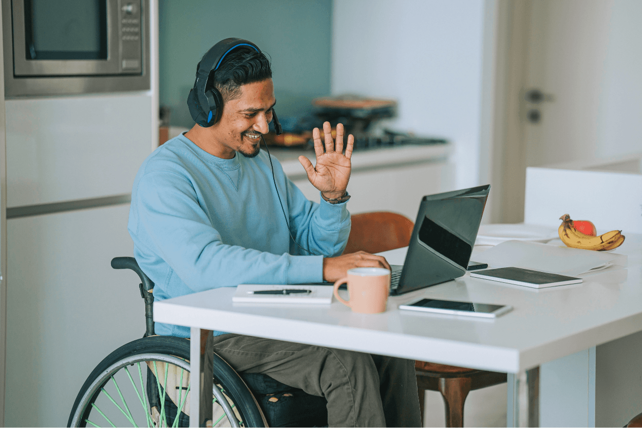 A man talking with headphones looking at a laptop