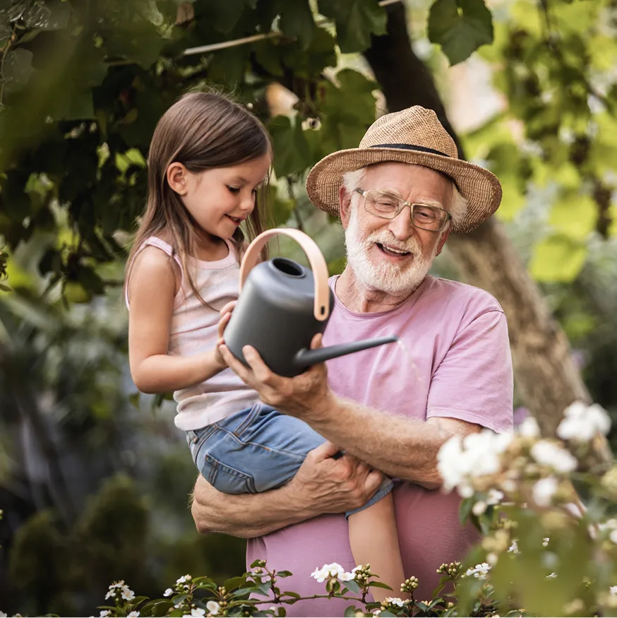 A man with a child watering plants in the garden