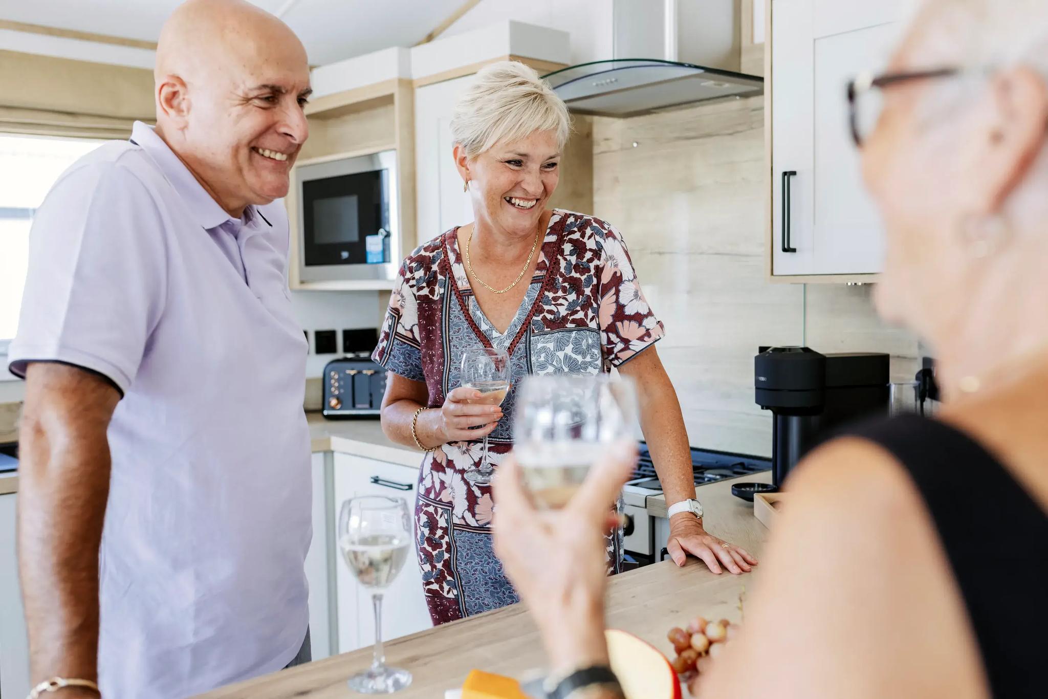 Couple with friends celebrating with glass of wine in their new holiday home