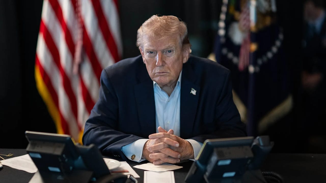 US President sat at desk hands clasped