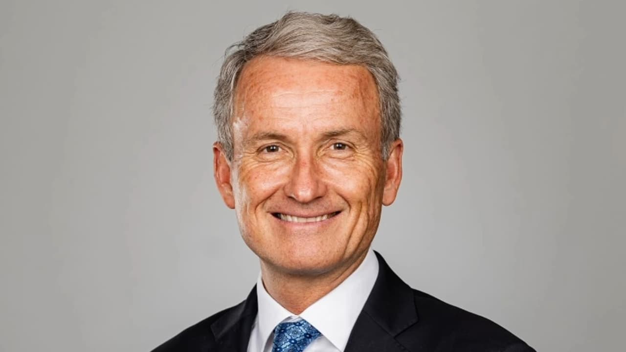 middle aged white man with grey hair wearing dark suit