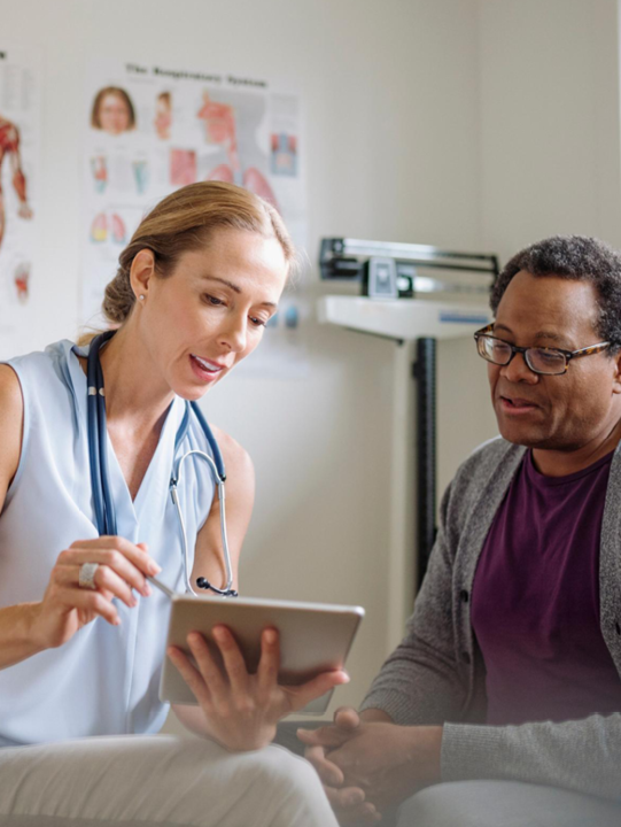 Ärztin erklärt einem Patienten mit CED die Diagnose anhand eines Tablets.