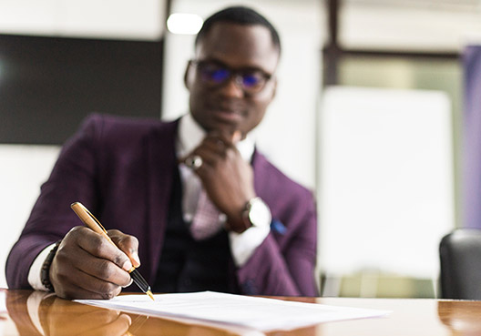 man sitting at his desk writing in a notebook man sitting at his desk writing in a notebook