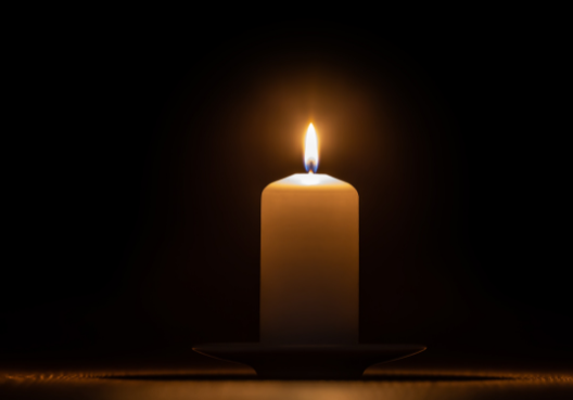 Mourners light a candle at a funeral service. A lit candle at a funeral.
