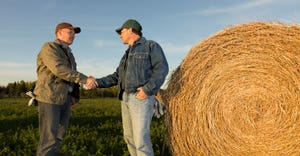 A landowner and farmer have a discussion in the field