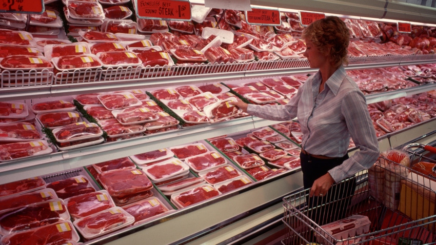 a woman in grocery store shopping for meat