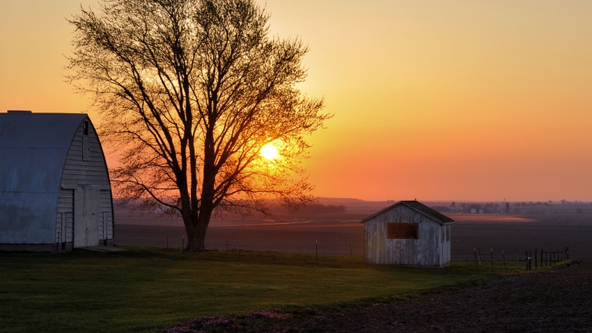 sunsetting behind field and shed