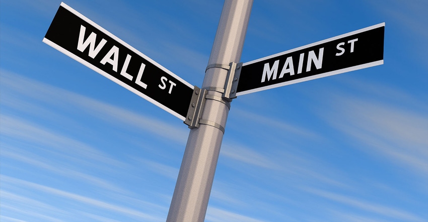 Wall Street and Main Street signs on a pole. Blue sky.