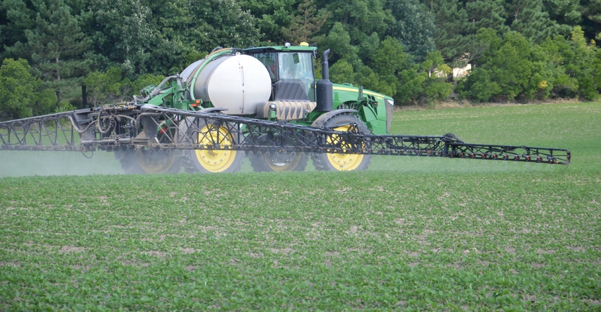 sprayer applying herbicide to soybean field