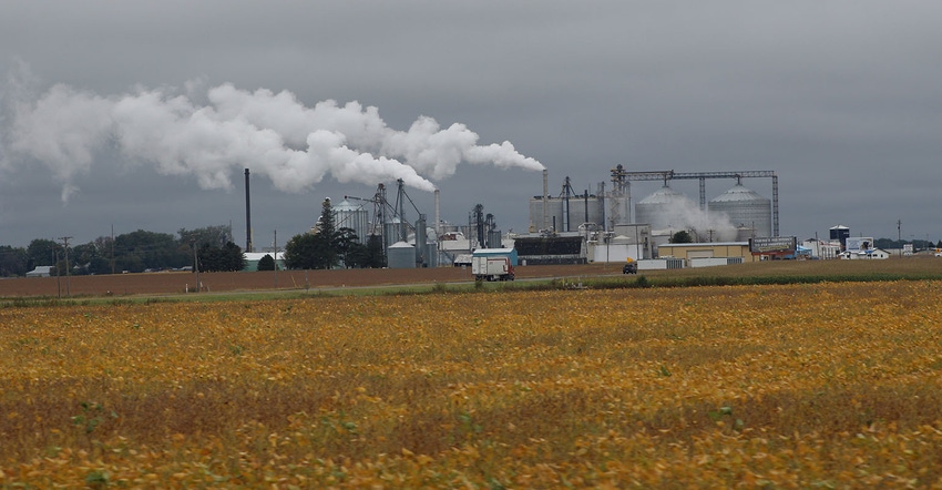 Ethanol plant beyond yellow field of soybeans