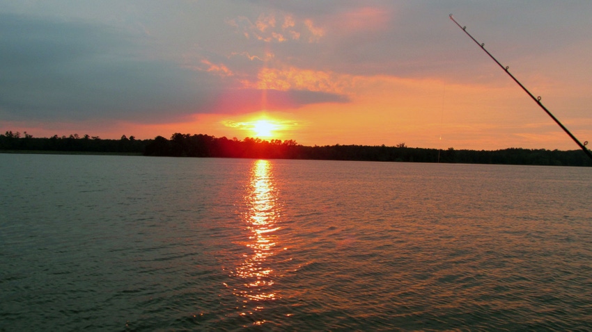 Sunset over a lake with fishing pole.