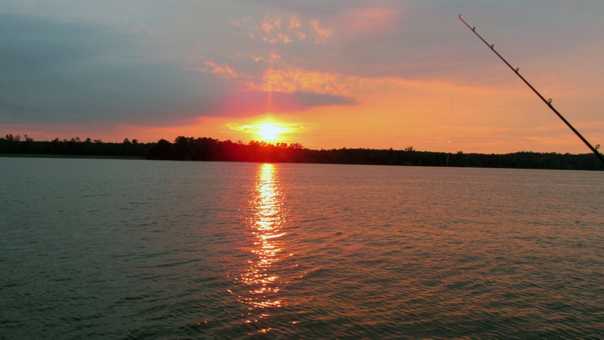 Sunset over a lake with fishing pole. Sunset over a lake with fishing pole.