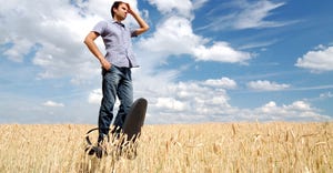 Man standing on office chair in a field looking for direction