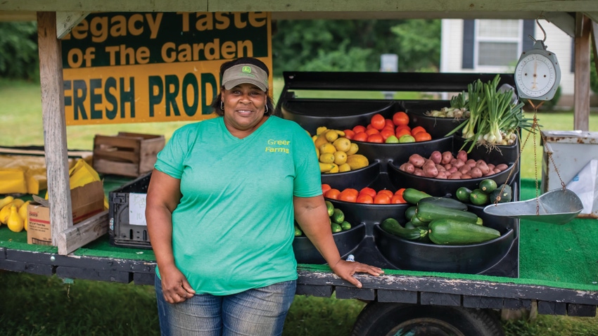 Denise Jamerson standing next to a produce farm stand