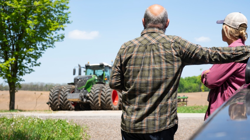  farming couple looking at a tractor contemplating a decision