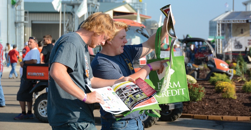 two young men looking at show program at farm show