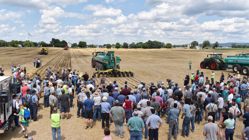 A large crowd gathers near a manure spreading demonstration