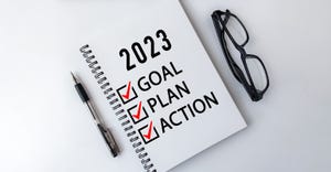 2023 Goal, Plan, Action checklist text on note pad with laptop, glasses and pen.