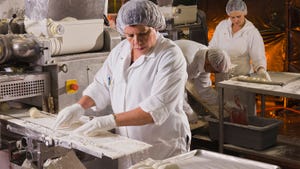 People in hair nets and white coats working in a food processing plant