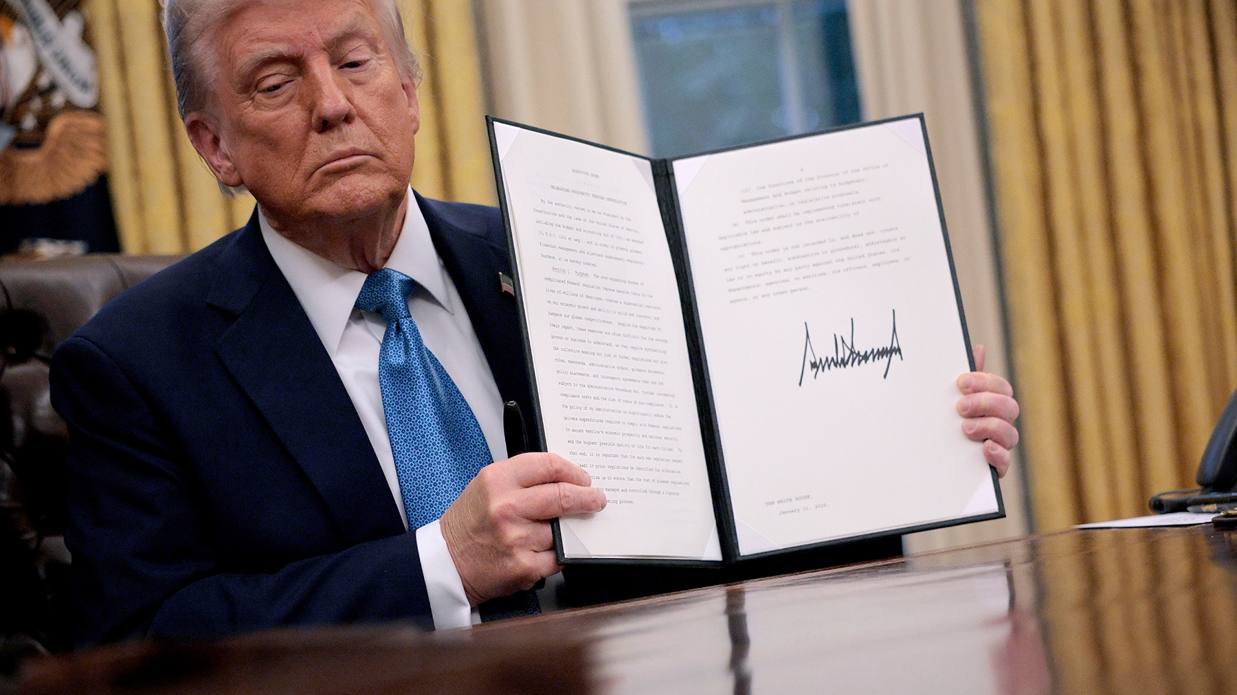 Trump holds up executive order document.