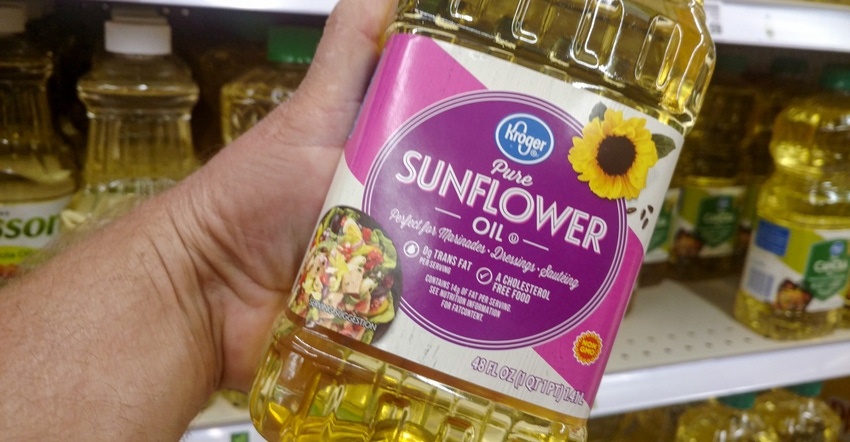 A male hand holding a bottle of Kroger brand sunflower oil