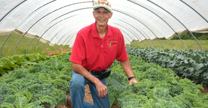 Art King kneeling in greenhouse Art King kneeling in greenhouse
