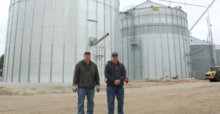 Alex and Paul Schutjer in front of a 120,000-bushel dry storage bin 