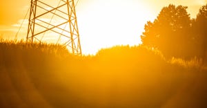 silhouette of electrical tower in field at sunset 