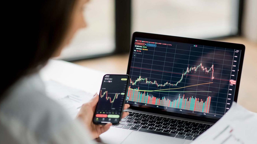 Woman analyzing market charts on laptop and phone screens