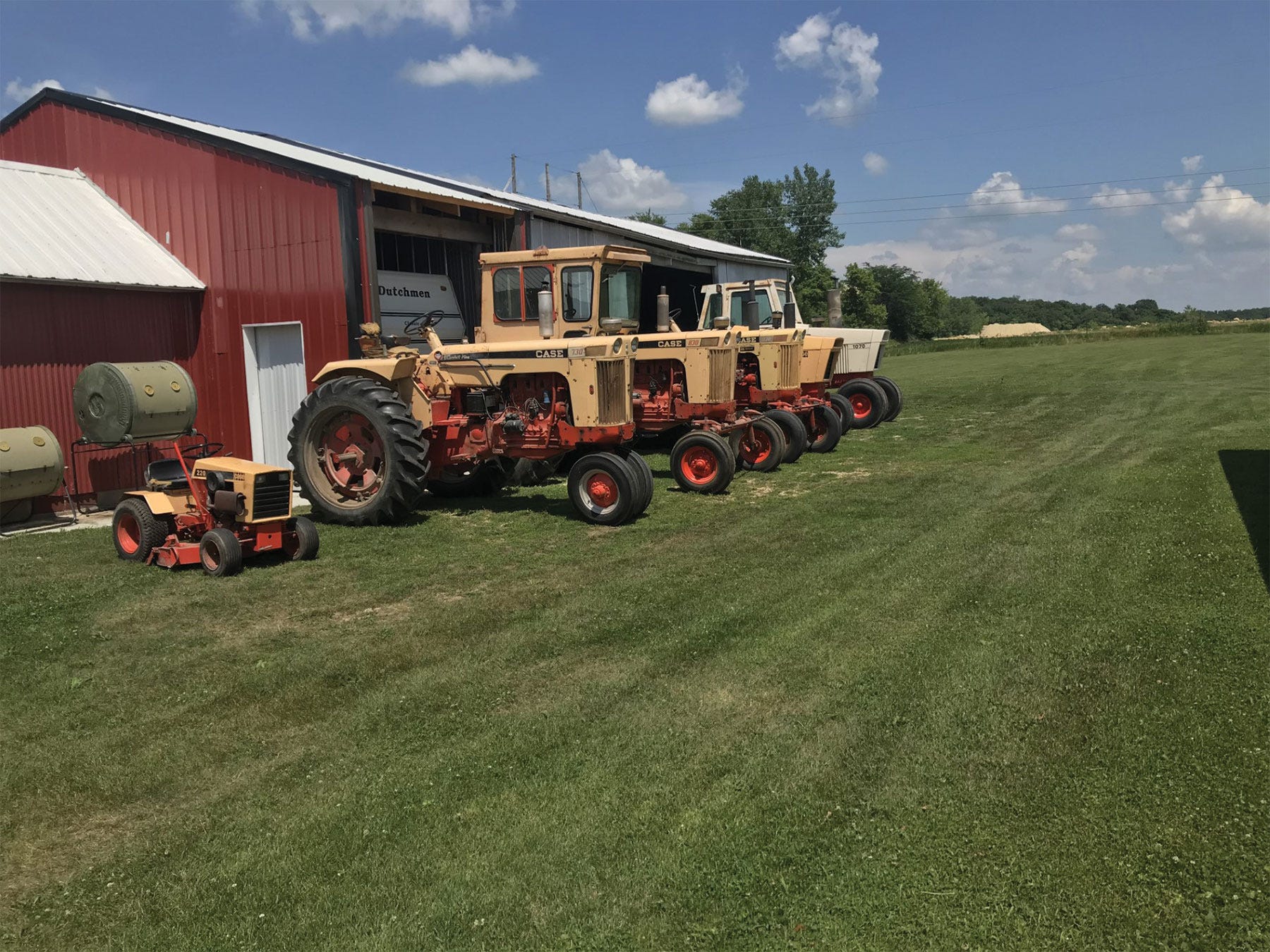antique tractors lined up along a red shed