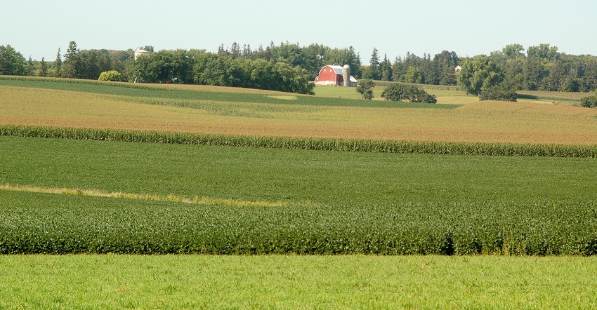 crop field with farmstead in distance crop field with farmstead in distance