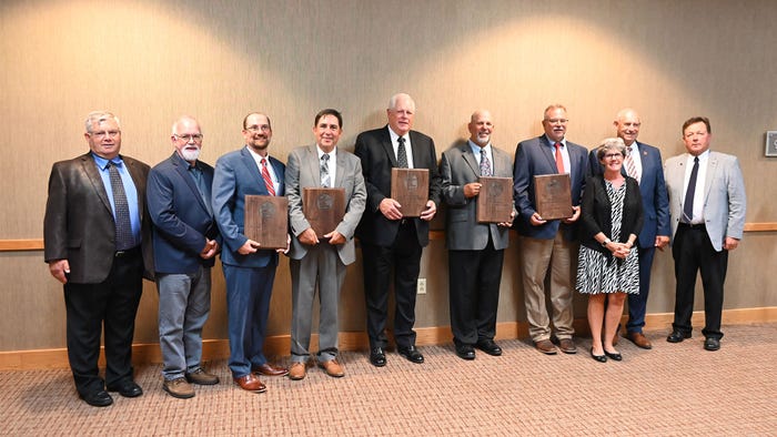 A group of people holding wooden plaques stand in a line and smile at the camera