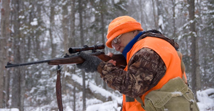 Hunter taking aim at a deer on a snowy day