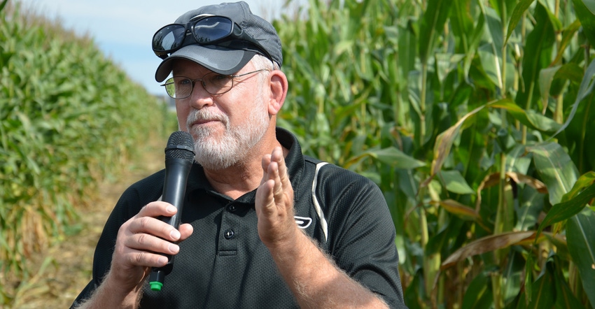Bob Nielsen speaking into microphone in front of cornfield Bob Nielsen speaking into microphone in front of cornfield