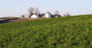 field with farm and silo in the background