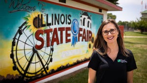 Woman in glasses posing in front of an Illinois State Fair mural