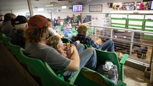 Dan and 1-year-old daughter Clare Haynes sit in the stands during a cattle sale