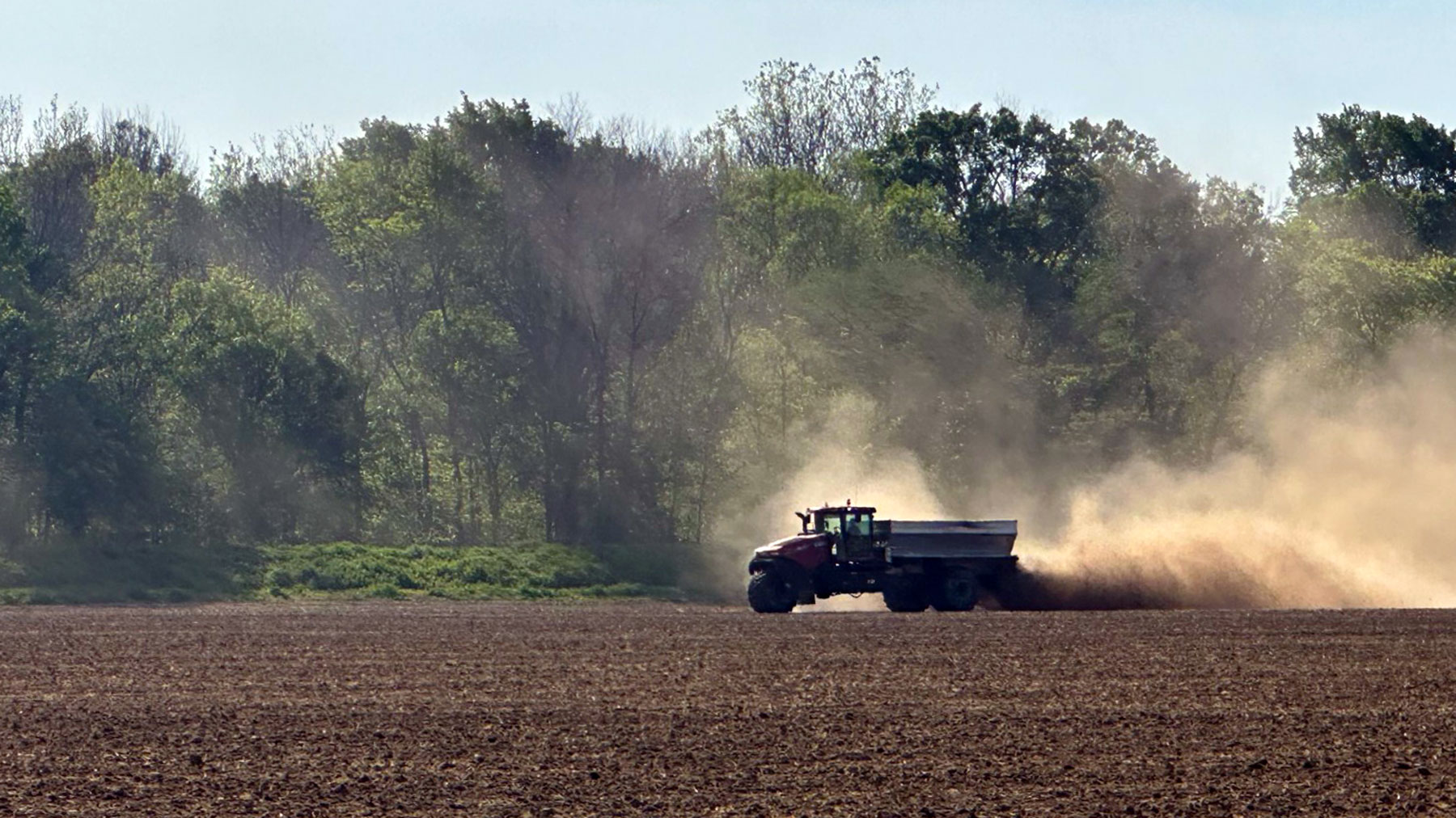 Chicken litter truck spreading litter across an unplanted field.