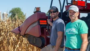 Don and Steven Schlesselman smile for a photograph near a harvested cornfield