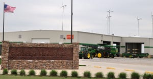 Wind turbines behind building with tractors 