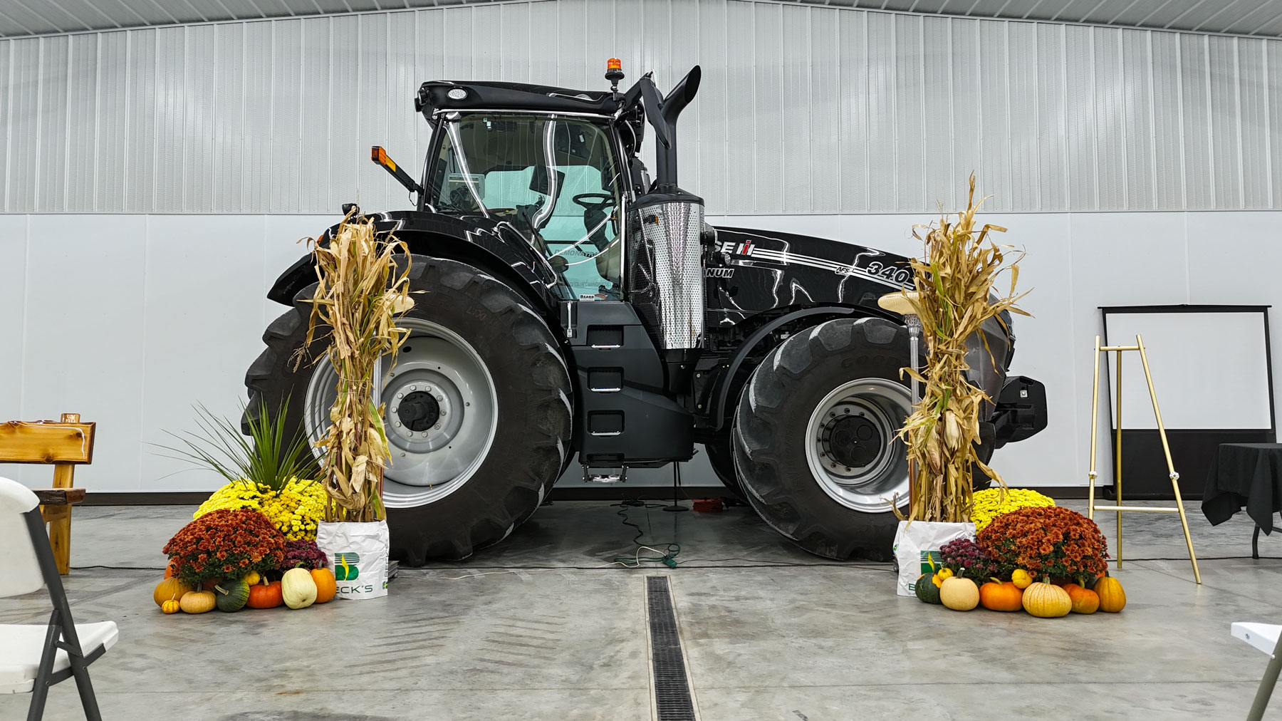 A Case IH Magnum 340 Black Knight tractor flanked by corn shocks, potted mums and pumpkins