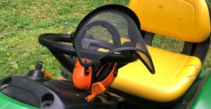 mesh visor with ear protectors perched on riding lawnmower
