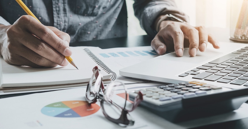 man's hands with pencil, laptop keyboard, calculator, eyeglasses