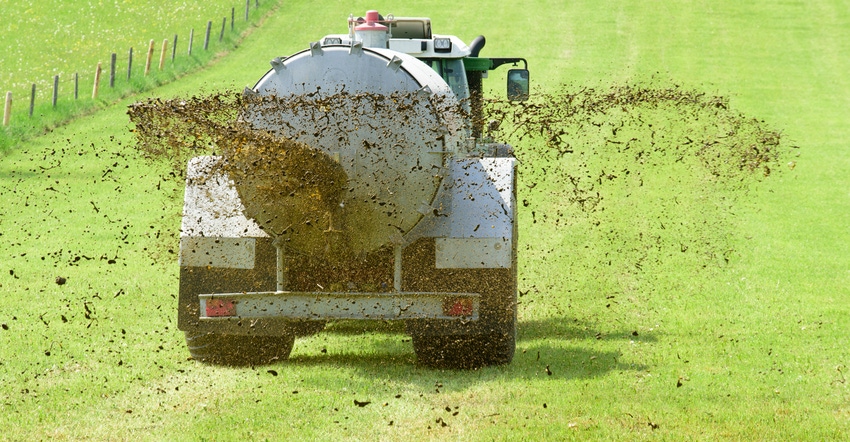 tractor spreading liquid manure on field