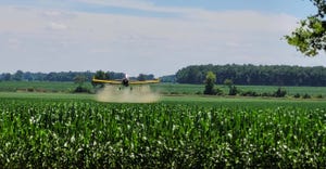 Airplane applying fungicide to corn field